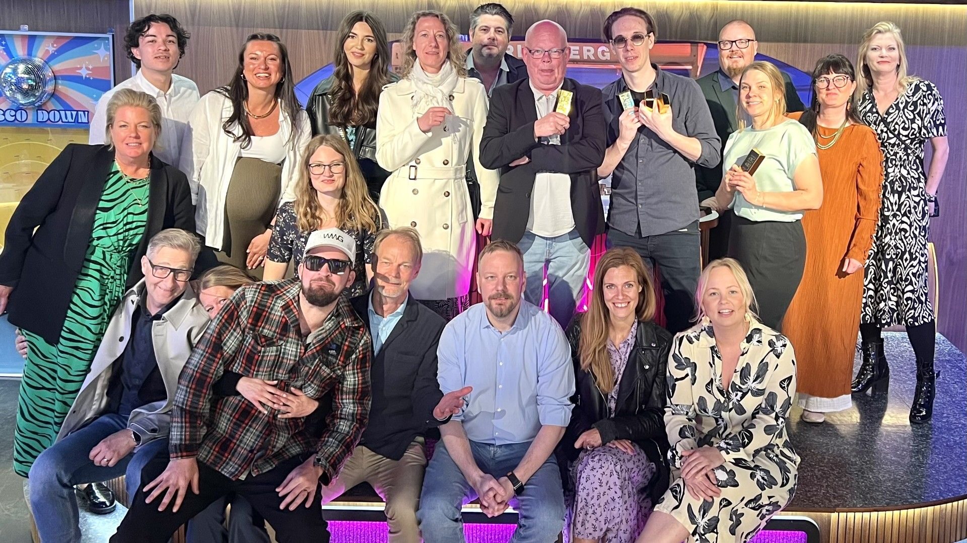 Grupp av människor som poserar glatt tillsammans inomhus.