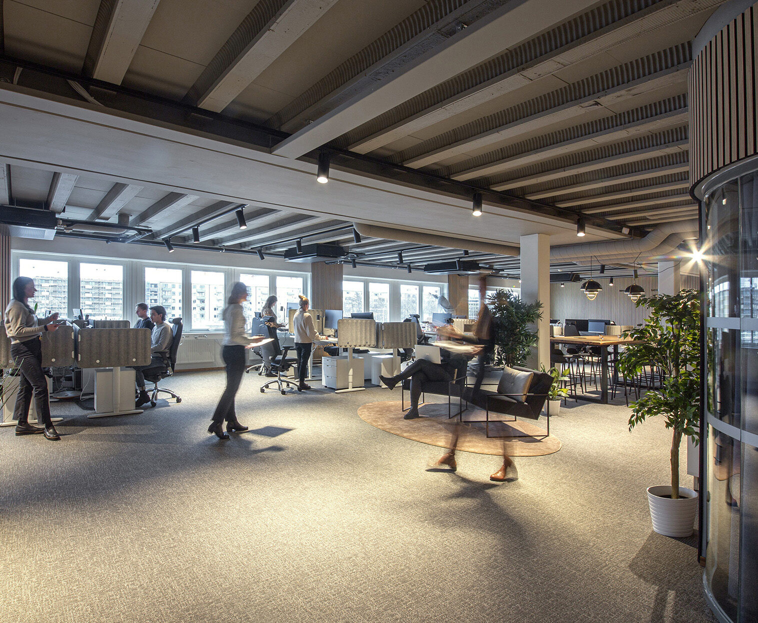 Modernt kontorslandskap med medarbetare och öppet ljusinsläpp.